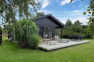 a small cabin with a table and chairs on a deck at 12215-Sjaellands-Odde-Granitager-8 in Tjørneholm