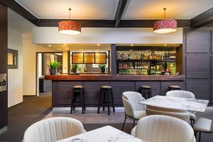 a bar in a restaurant with white chairs and tables at Grand Riccarton Hotel in Christchurch