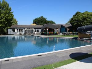 a large swimming pool in front of a building at Chalet in Gelderland with Hot Tub in Lathum +30 photos