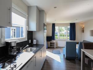 a kitchen with a sink and a living room at Chalet in Gelderland with Hot Tub in Lathum