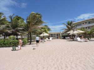 a group of people walking on the beach at Apartamento Pé na Areia Porto das Dunas - Paraiso das Dunas in Aquiraz