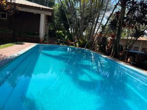ein großer blauer Swimmingpool vor einem Haus in der Unterkunft El Guembe Hostel House in Puerto Iguazú
