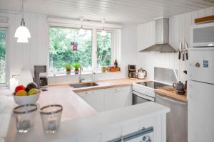 une cuisine blanche avec un bol de fruits sur le comptoir dans l'établissement 12251-1-Sjaellands-Odde-Hyggebovej-3, à Tjørneholm 15 autres photos
