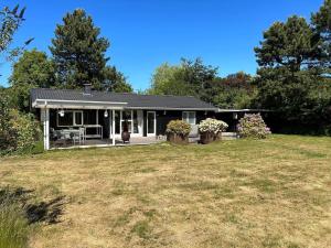 une petite maison blanche avec une cour dans l'établissement 12251-1-Sjaellands-Odde-Hyggebovej-3, à Tjørneholm