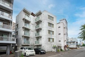 een wit gebouw met twee auto's ervoor geparkeerd bij Anax Nord 203 in Sapporo