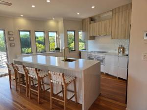 una cucina con ampia isola bianca con sgabelli da bar di Beachside House in Sebel Resort a Twin Waters
