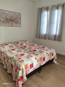 a bedroom with a bed with a colorful quilt on it at Flat novo - Central - Vila Exposição - Garantia de conforto e satisfação in Montes Claros