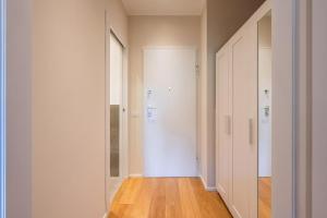 an empty hallway with a white door and wooden floors at Vaga's Nest - Modern Studio Apartment in Milan