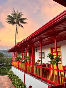ein Haus mit einem roten Balkon mit einer Palme in der Unterkunft Coronel's Peak Coffee House in Salento