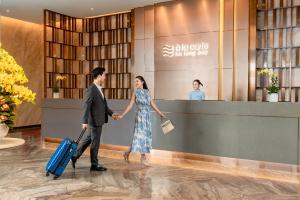 Ein Mann und eine Frau gehen durch eine Lobby mit Gepäck in der Unterkunft A La Carte Ha Long Bay Managed by TASECO in Hạ Long + 177 Fotos