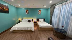 two beds in a room with blue walls at Dream Hotel Hà Nội in Hanoi
