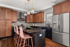 a kitchen with wooden cabinets and a island with pink bar stools at Nashville 4 Bedroom House with Hot Tub and Backyard Close to Downtown in Nashville