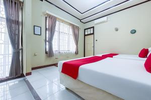 a bedroom with a large white bed with red sheets at RedDoorz Syariah at Flamboyan Indah Kuningan in Sangkanurip