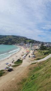 a beach with a bunch of people and the ocean at Prainha Arraial do Cabo Loft in Arraial do Cabo