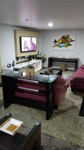 a living room with a couch and a tv at Prainha Arraial do Cabo Loft in Arraial do Cabo