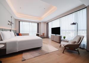 a bedroom with a large white bed and a chair at Novotel Xiamen Downtown in Xiamen