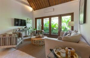 a living room with a couch and a table at Three Bedrooms Elegant Home The White Door Villa in Sanur