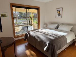 a bedroom with a bed and a large window at Barossa Garden Homestay in Williamstown