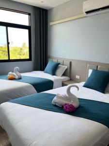 a hotel room with three beds with swans on them at UPMOON Hotel Chalong Phuket in Ban Suan +42 photos