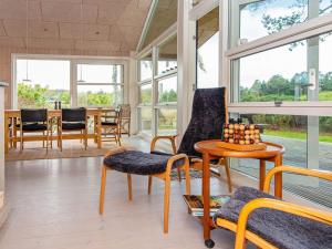 a living room with a table and chairs and windows at 6 person holiday home in Glesborg-By Traum in Bønnerup
