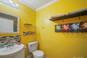 a yellow bathroom with a toilet and a sink at Mountain Cottage on 7 Acres in Tryon +19 photos