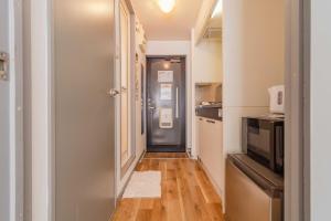 a hallway with a door to a kitchen with a microwave at Wajiro Good Place House in Fukuoka