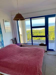 ヘルマナスにあるPitkindie Oceanfront Escapeの大きなベッドと大きな窓のある寝室