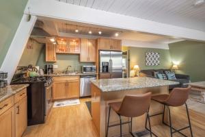 a kitchen with wooden cabinets and a kitchen island with bar stools at Moonlight Memories Jacuzzi, Theatre, Dogs Okay! in Big Bear Lake