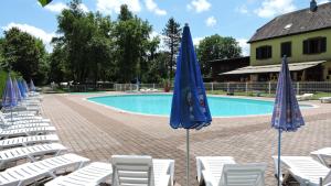un gruppo di sedie e ombrelloni accanto a una piscina di Camping Les Lupins a Seppois-le-Bas