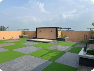 un patio con césped verde y un edificio en Vibrant Vision Near Airport with Coffee Maker & Wifi, en Pune