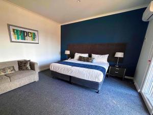 a bedroom with a bed and a couch at Golden Age Motor Inn in Queanbeyan