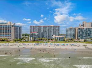 eine Gruppe von Menschen an einem Strand mit Gebäuden in der Unterkunft Grande Cayman 1BR Penthouse Patio Oceanfront Views in Myrtle Beach