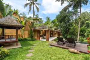 a garden with two chairs and a house at Samkhya Villas - Free 1x Floating Breakfast or Minibar in Ubud