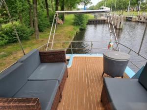 ein Boot mit einer Couch auf dem Deck eines Flusses in der Unterkunft Gezellig overnachten luxe boot in De Punt