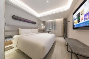 a bedroom with a white bed and a flat screen tv at Atour X Hotel, Dongguan Street, Daming Lake,Jinan in Jinan
