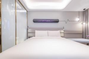 a bed in a room with a thermometer on the wall at Atour X Hotel, Dongguan Street, Daming Lake,Jinan in Jinan