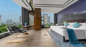 a bedroom with a large bed with a chair and a chair at Xana Hotelle·Hotel Luzhou Baizitu Square in Luzhou