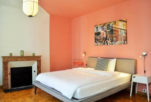 a bedroom with an orange wall with a bed and a fireplace at B&B Louis-Favre 21 in Neuchâtel