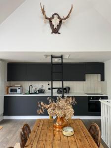a kitchen with a wooden table with a vase of flowers at The Lodge in Kent +18 photos