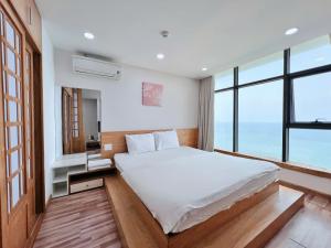una camera da letto con un grande letto bianco e finestre di Gold Ocean Apartment Nha Trang a Nha Trang
