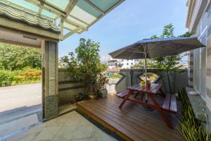 a wooden deck with a picnic table and an umbrella at Hualien Macaron B&B in Ji'an