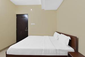 a bedroom with a white bed with a black door at Hotel O Ashoka in Kota