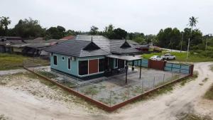a small house on a dirt road next to a lot at Aman Homestay, Marang in Marang