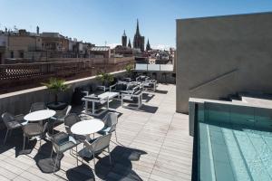 a rooftop patio with tables and chairs and a swimming pool at Catalonia Magdalenes in Barcelona