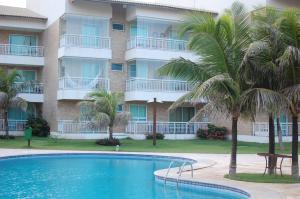 una piscina frente a un edificio con palmeras en Apartamento Pé na Areia Porto das Dunas - Paraiso das Dunas, en Aquiraz