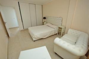 a bedroom with a bed and a couch and a chair at Flor do Mar House in Ponta Delgada