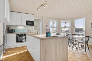 a kitchen with white cabinets and a table with chairs at 8124-Ronde-Rytterparken-33 in Rønde