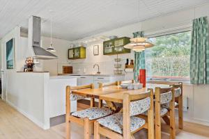 une cuisine et une salle à manger avec une table et des chaises en bois dans l'établissement 84176-Ebeltoft-Birkevej-10, à Ebeltoft