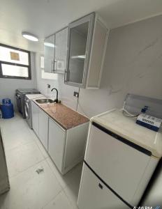 a small kitchen with white cabinets and a sink at New Manaser apartment in Al Ain