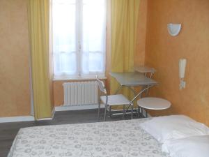 a bedroom with a bed and a desk and a window at Hotel Restaurant Bocher in Ploubazlanec